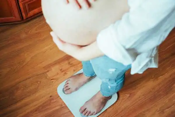 Image of woman weighing herself and experiencing weight gain through pregnancy Ross-on-Wye